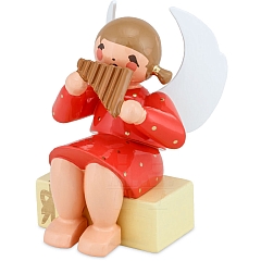 Engel sitzend auf Geschenkpaket mit Panflöte rot